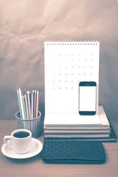 office desk : coffee with phone,wallet,calendar,color pencil box,stack of book on wood background vintage style
