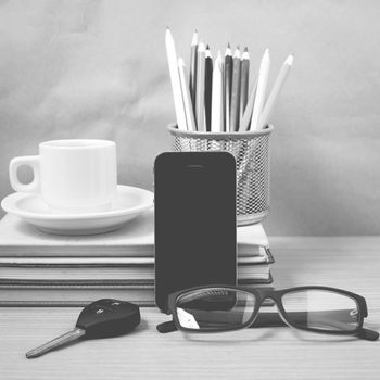 office desk : coffee and phone with car key,eyeglasses,stack of book,pencil box black and white color