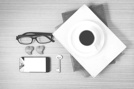 office desk : coffee and phone with key,eyeglasses,stack of book,heart on wood background black and white color