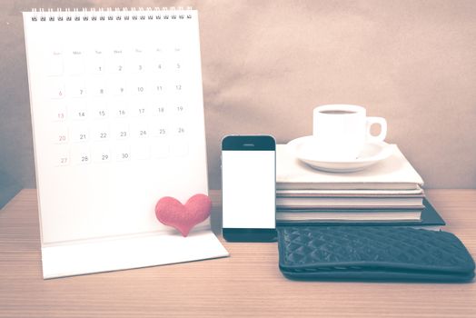 office desk : coffee with phone,wallet,calendar,heart,stack of book on wood background vintage style