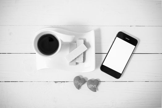 coffee cup with wafer,phone,heart on white wood background black and white color