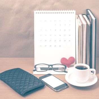 desktop : coffee with phone,stack of book,wallet,heart,eyeglasses,calendar on wood background vintage style