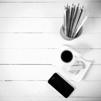 coffee cup with wafer,phone,pencil box on white wood background black and white color