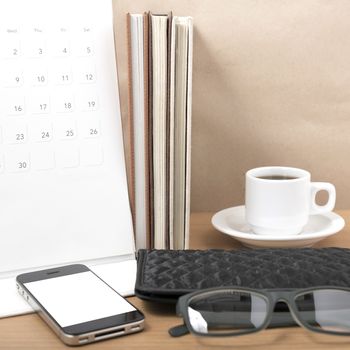 office desk : coffee with phone,stack of book,eyeglasses,wallet,calendar on wood background