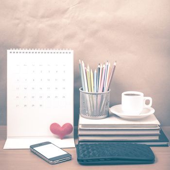 office desk : coffee with phone,wallet,calendar,heart,color pencil box,stack of book,heart on wood background vintage style