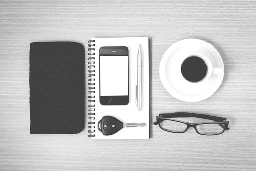 coffee and phone with notepad,car key,eyeglasses and wallet on wood table background black and white color