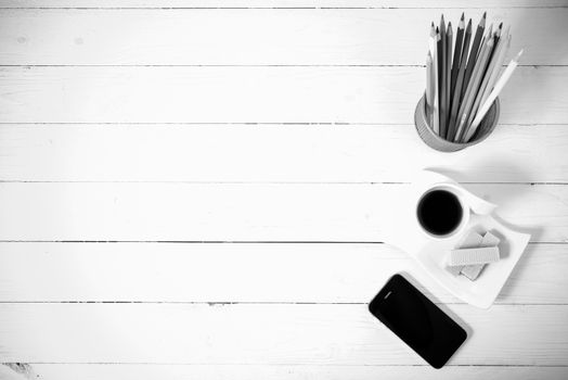 coffee cup with wafer,phone,pencil box on white wood background black and white color