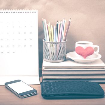 office desk : coffee with phone,wallet,calendar,heart,color pencil box,stack of book,heart on wood background vintage style