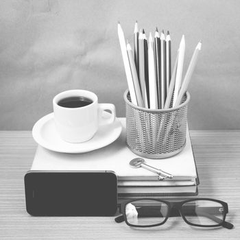 office desk : coffee and phone with key,eyeglasses,stack of book,pencil box black and white color