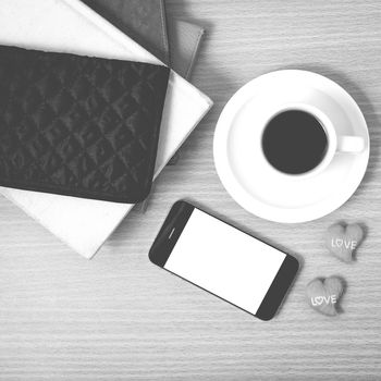 office desk : coffee with phone,stack of book,wallet on wood background black and white color