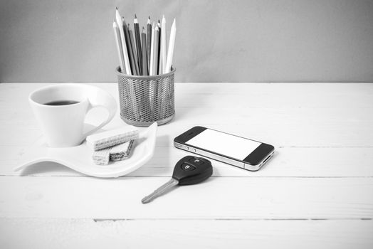 coffee cup with wafer,phone,pencil box,car key on white wood background black and white color