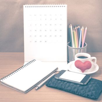 office desk : coffee with phone,wallet,calendar,heart,color pencil box,notepad,heart on wood background vintage style