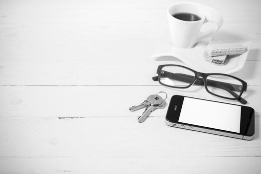 coffee cup with wafer,phone,key,eyeglasses on white wood background black and white color