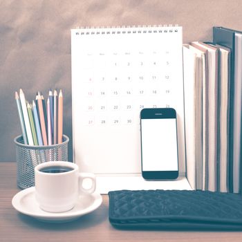 office desk : coffee with phone,wallet,calendar,color pencil box,stack of book on wood background vintage style