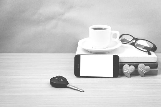 office desk : coffee and phone with car key,eyeglasses,stack of book,heart on wood background black and white color