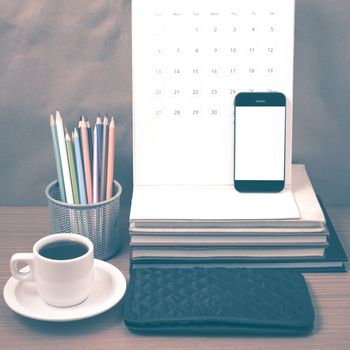 office desk : coffee with phone,wallet,calendar,color pencil box,stack of book on wood background vintage style