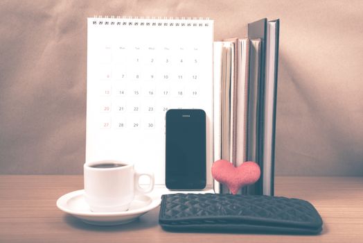 office desk : coffee with phone,wallet,calendar,heart,stack of book on wood background vintage style