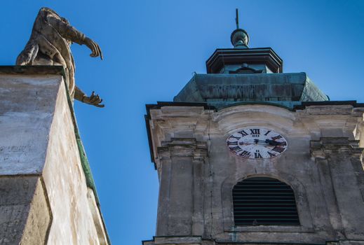 Statue of a saint and a tower with clocks. Church of Saint Cross in Devin, Bratislava, Slovakia.