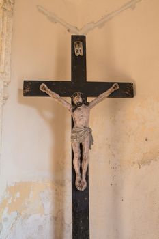 Wooden cross with crucified Jesus Christ in the entrance to the church. Enlightened by sunlight.