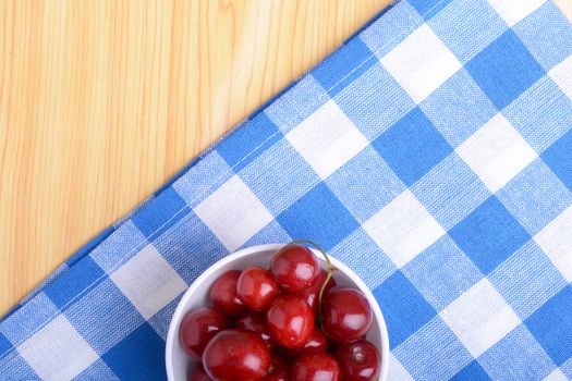 Red ripe cherries in a white bowl