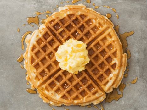 close up of rustic traditional waffle with butter and maple syrup