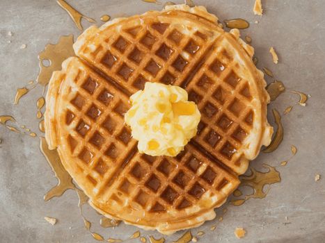 close up of rustic traditional waffle with butter and maple syrup
