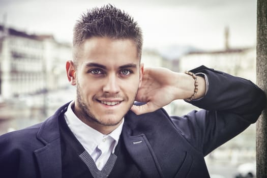 Handsome young man outdoor wearing jacket and shirt standing by historic building in European city. Turin, Italy