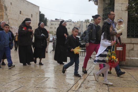 WEST BANK, Bethlehem: Palestinian Catholics walk to the Church of the Nativity Compound, to celebrate the Palm Sunday on March 20, 2016 in the West Bank city of Bethlehem. Palm Sunday marks the triumphant return of Jesus Christ to Jerusalem when a cheering crowd greeted him waving palm leaves, a week before his crucifixion.