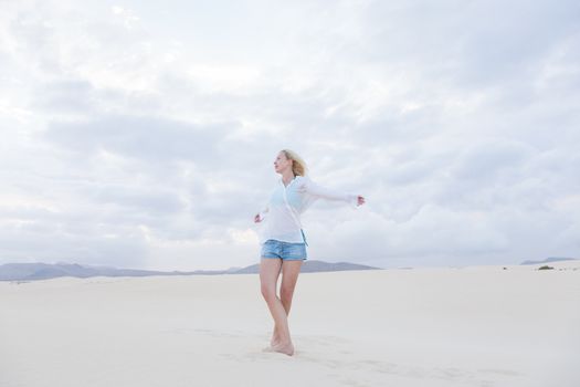 Relaxed woman enjoying freedom feeling happy at beach in the morning. Serene relaxing woman in pure happiness and elated enjoyment with arms outstretched. Copy space.