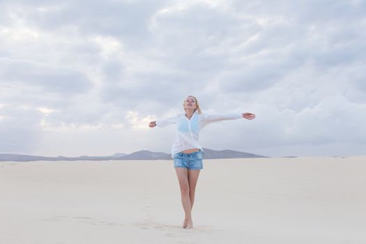 Relaxed woman enjoying freedom feeling happy at beach in the morning. Serene relaxing woman in pure happiness and elated enjoyment with arms outstretched. Copy space.