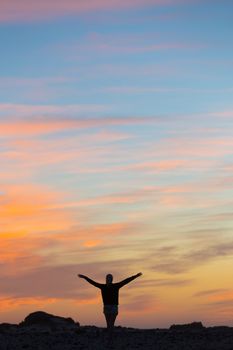 Silhouette of free woman enjoying freedom feeling happy at sunset. Serene relaxing woman in pure happiness and elated enjoyment with arms raised outstretched up. 