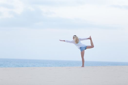 Relaxed woman enjoying enjoying peace and freedom during her morning walk on vacations, streching in yoga like pose at beach.