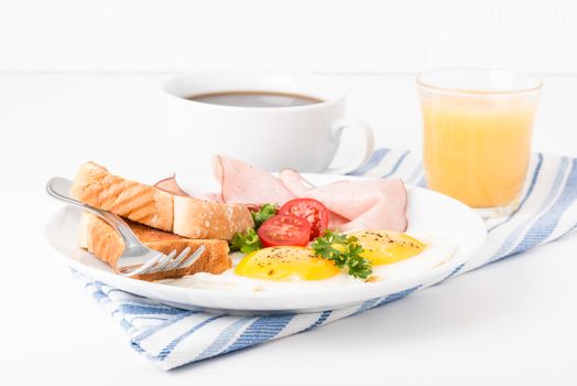 Eggs sunny side up served with ham and toast.