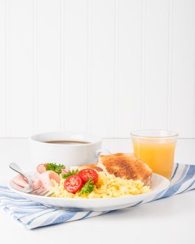 Portrait view of a plate of scrambled eggs and ham.