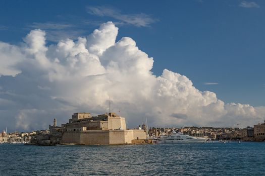 VALETTA, MALTA - NOVEMBER 2, 2015 : View of Valletta with ships and boats on coastline, on cloudy sky background.