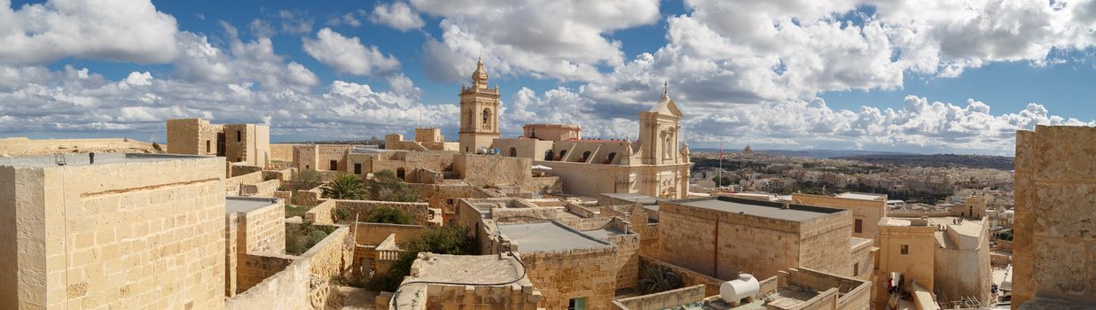 View of Cittadella, historical fortified small city of Cittadella with limestone structures, on cloudy blue sky background.