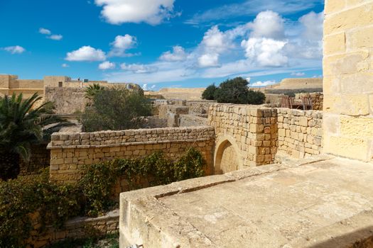 View of Cittadella, historical fortified small city of Cittadella with limestone structures, on cloudy blue sky background.