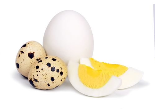 A few unpeeled boiled chicken and quail eggs and two slices of eggs isolated on a white background.