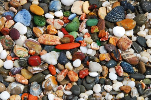 Multicolored sea pebbles on the shore for background or wallpaper.