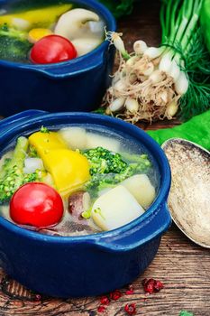 vegetable soup with peppers,potatoes,mushrooms and cauliflower on wooden background