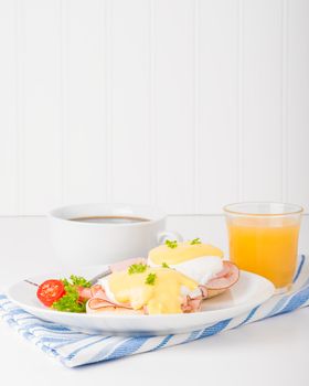Delicious eggs benedict served with fresh coffee and juice.