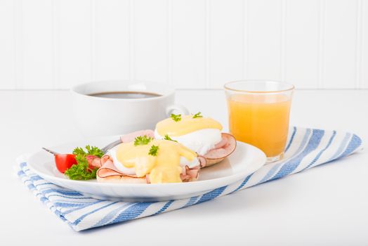 Delicious eggs benedict served with fresh coffee and orange juice.