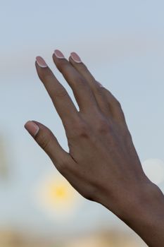 arm girls with beautiful manicure on a background of the blue sky