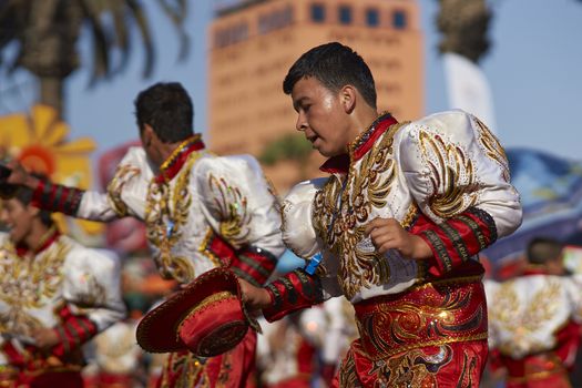 Male Caporales dancers in ornate costumes performing at the annual Carnaval Andino con la Fuerza del Sol in Arica, Chile.