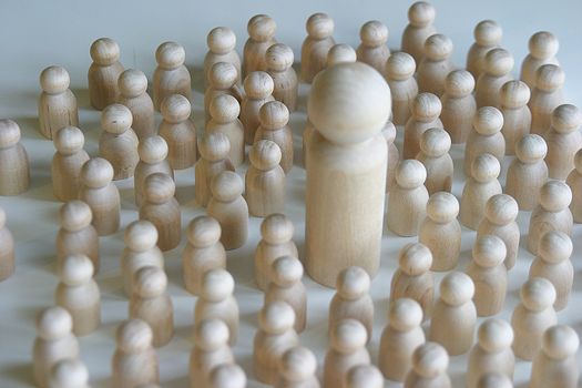 A collection of small little wooden figures gathering around one large wooden figure