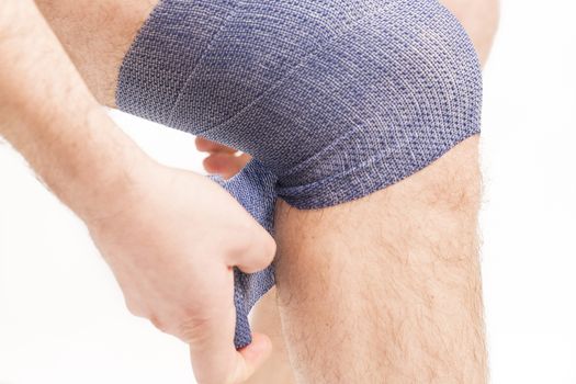 man putting  elastic bandage on knee pain health France