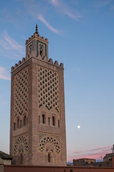 Minaret of a mosque at the main square in Marrakesh, in the time of a dusk, with still blue sky with some clouds.