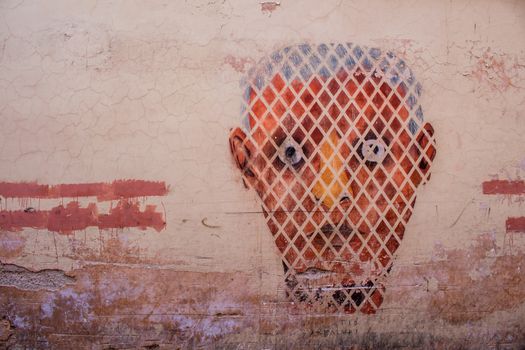 Wall in the medina of Marrakesh with graffiti of a textured man face.