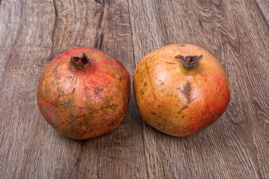 Two pomegranates on a brown wooden background