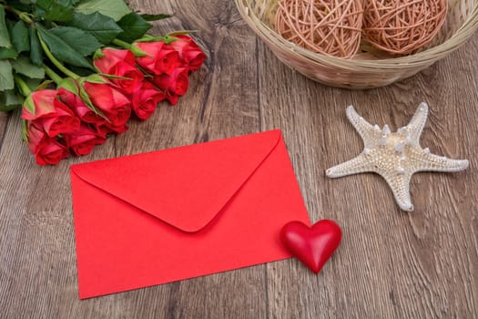 Red envelope, heart, starfish and red roses on a wooden background